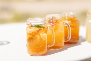 Image showing mason jars filled with a refreshing orange beverage, likely a summer drink, highlighting a vibrant and chilled beverage idea for outdoor events or gatherings.