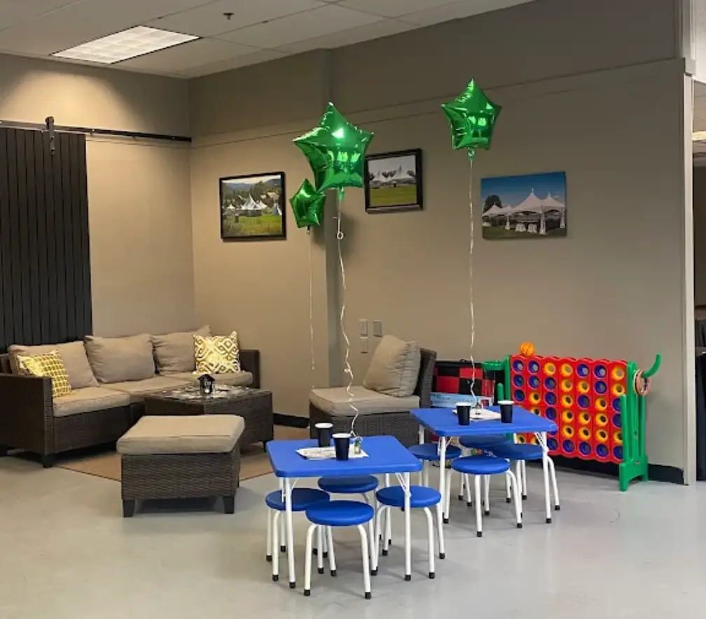 A cozy indoor space featuring child-friendly furniture, including blue tables and chairs, with playful decor like green star-shaped balloons, perfect for small event planning rental setups for kids.